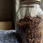 homemade granola in a canning jar next to a blug kitchen towel