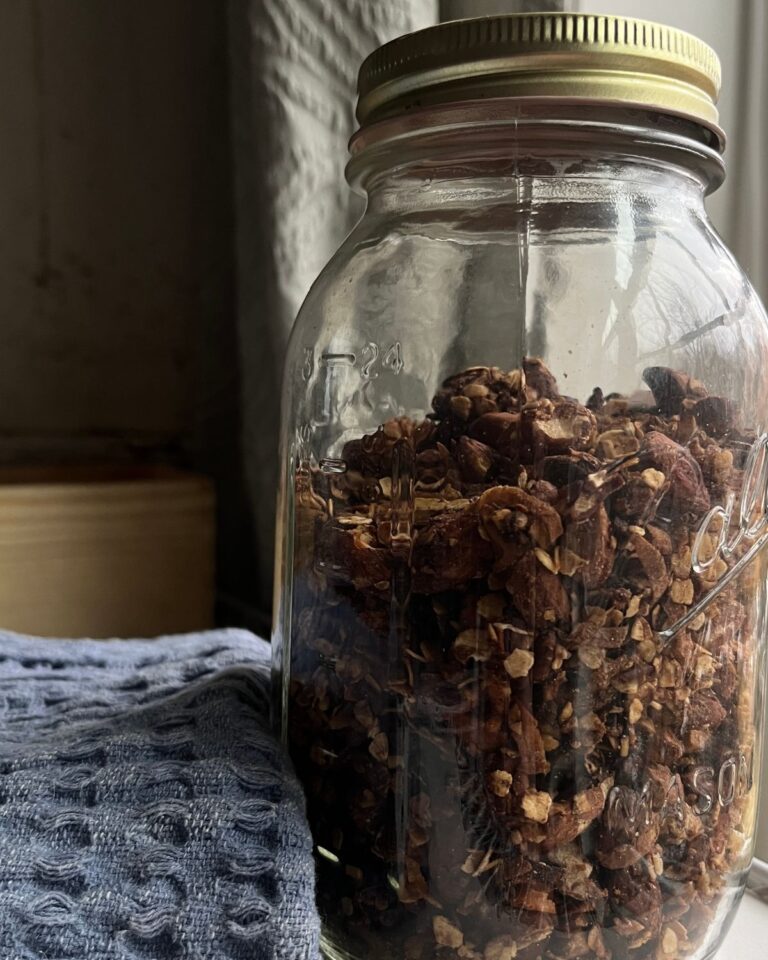 homemade granola in a canning jar next to a blug kitchen towel