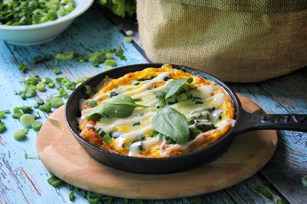 Delicious homemade frittata in a skillet, garnished with fresh spinach and cheese, perfect for brunch.