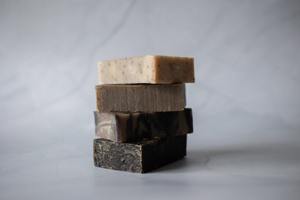 A minimalist image of a stack of handmade organic soaps on a marble surface.