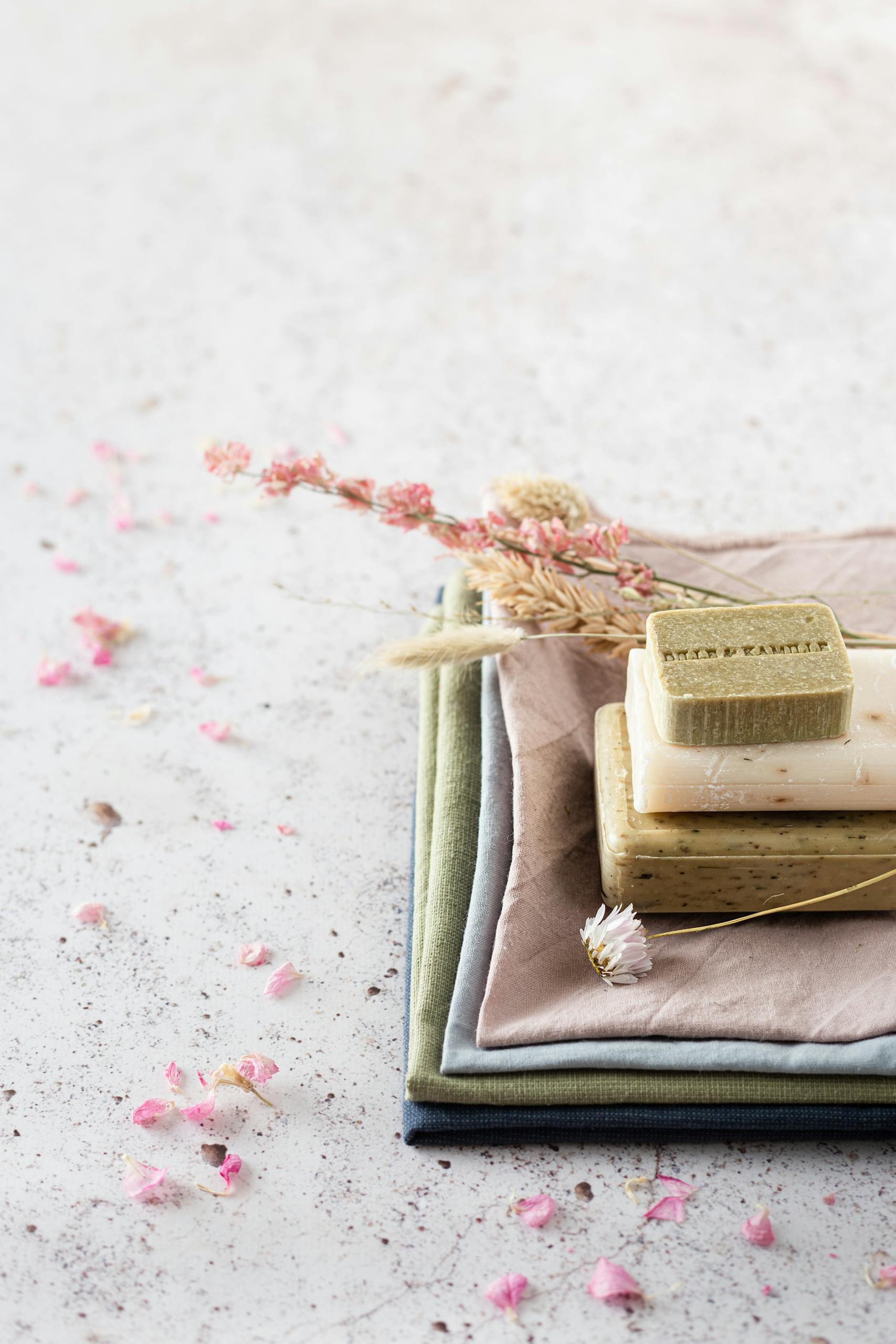Natural handmade soaps on layered textiles with dried flowers for a rustic aesthetic.