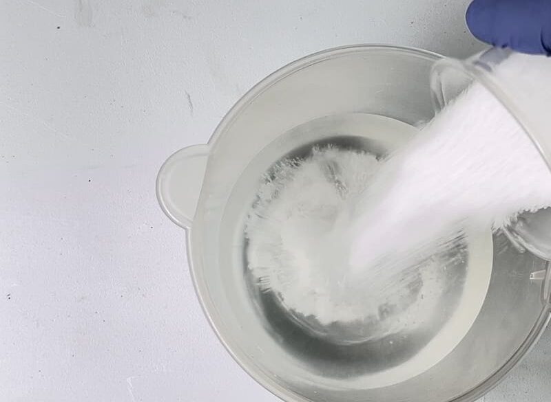 Lye being poured into a measuring cup containing water